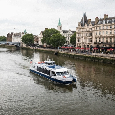 A modern river boat cruising along a scenic river with historical buildings in the background